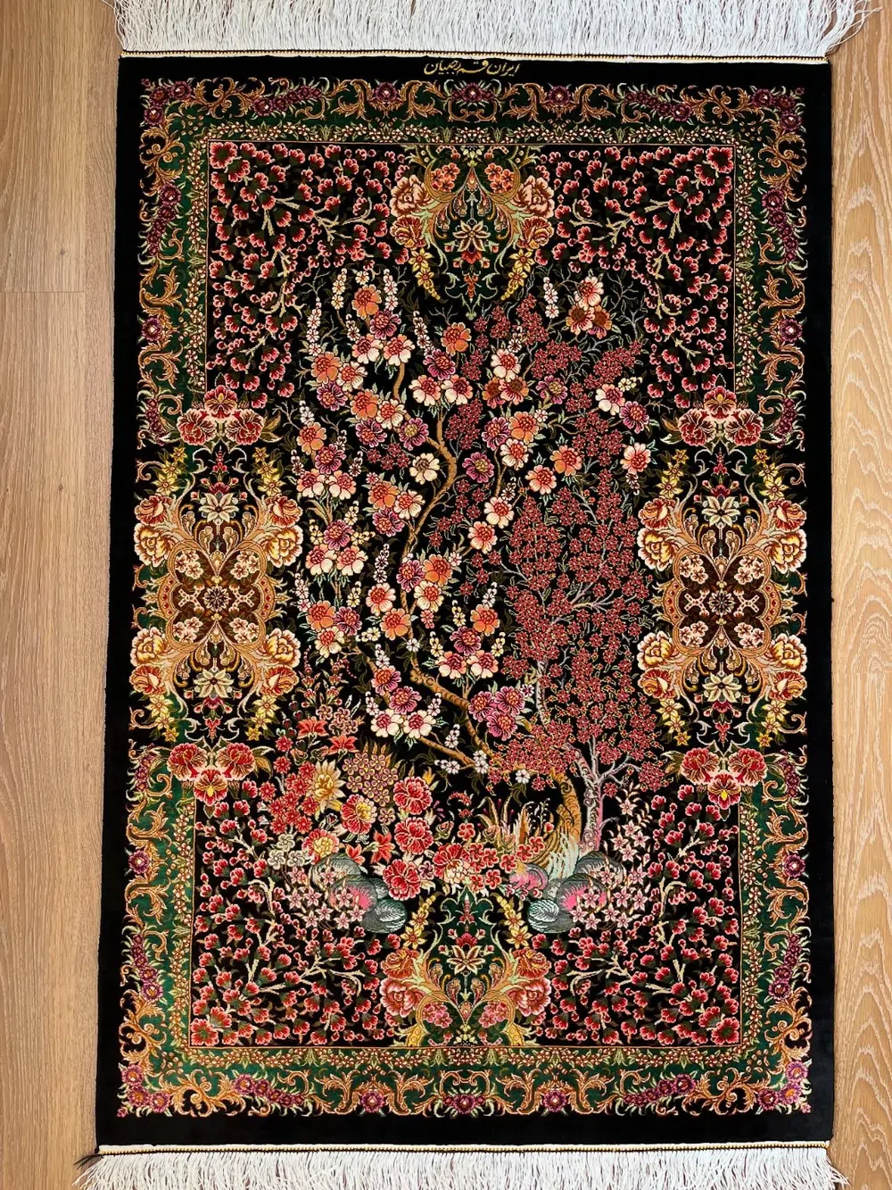 Crimson Orchard of Nightingales handmade Qom pure silk carpet with flowering trees, paired birds and an emerald floral border