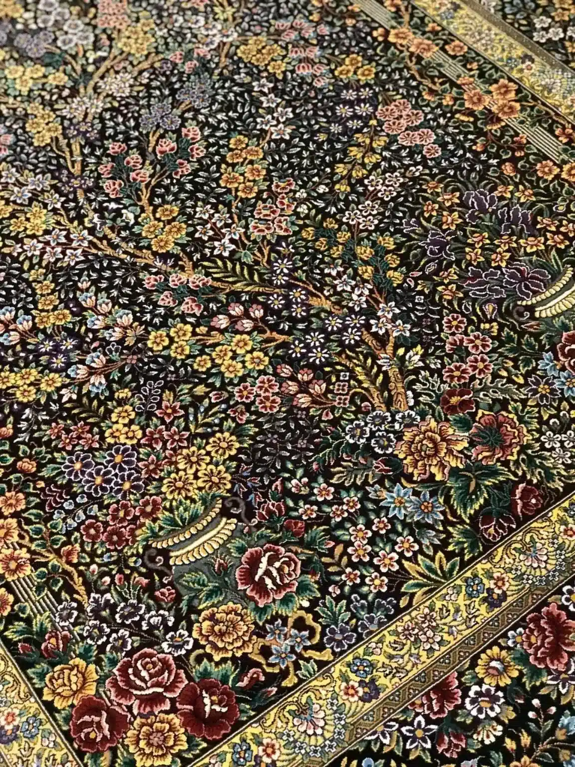 Midnight Blossom Canopy handmade Qom pure silk carpet featuring a dense flowering canopy of roses, blossoms and branching vines rendered against a luminous black silk field